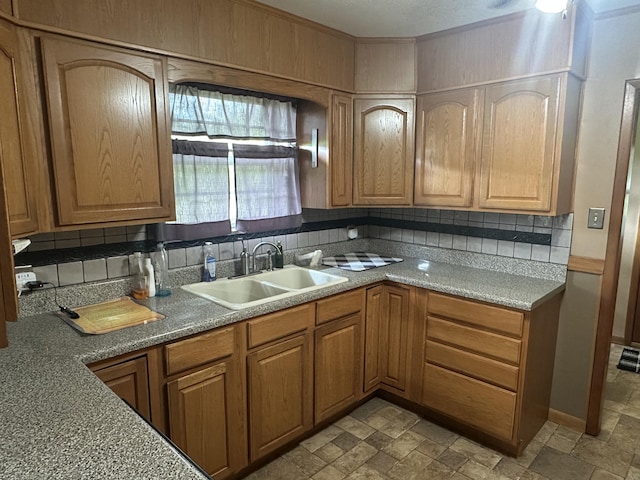 119 Cane Creek Rd, Rocky Top, TN 37769 - kitchen featuring a sink, backsplash, light stone finish flooring, baseboards, and brown cabinetry