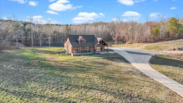 view of front of home featuring a front yard and a wooded view