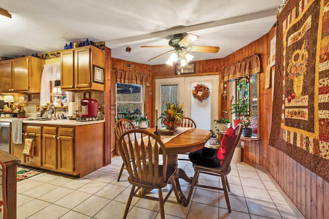 dining space with wooden walls, sink, ceiling fan, and light tile patterned floors