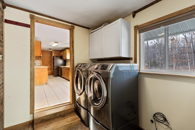 washroom with cabinet space, washing machine and dryer, and light tile patterned floors