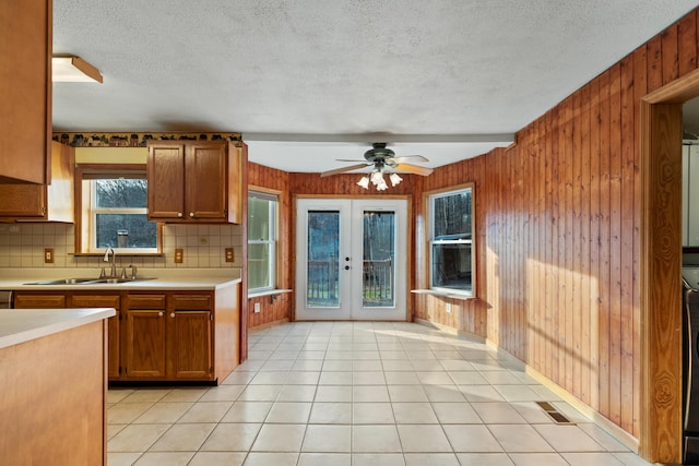 kitchen with brown cabinetry, light countertops, a sink, and wood walls