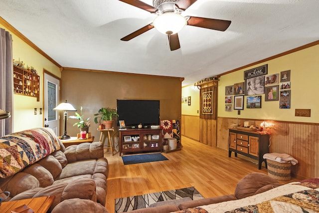 living room featuring hardwood / wood-style flooring, ceiling fan, crown molding, and a textured ceiling