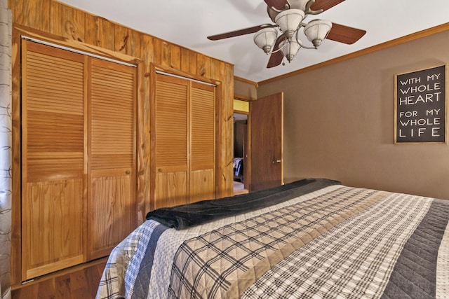 bedroom with ornamental molding, ceiling fan, and multiple closets