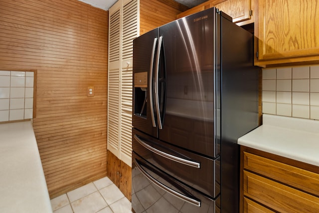 kitchen with brown cabinetry, light countertops, refrigerator with ice dispenser, and light tile patterned floors