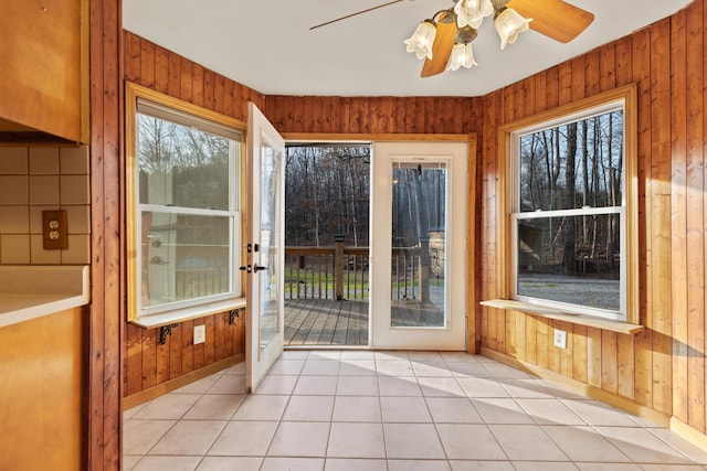 unfurnished sunroom featuring a ceiling fan and plenty of natural light