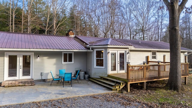 back of property with a patio area, a chimney, metal roof, and french doors