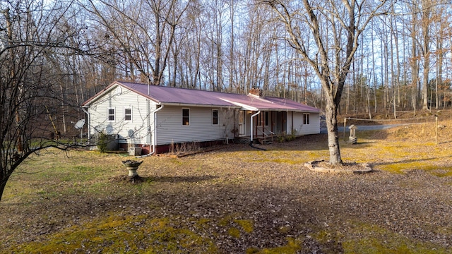 single story home with metal roof and a chimney