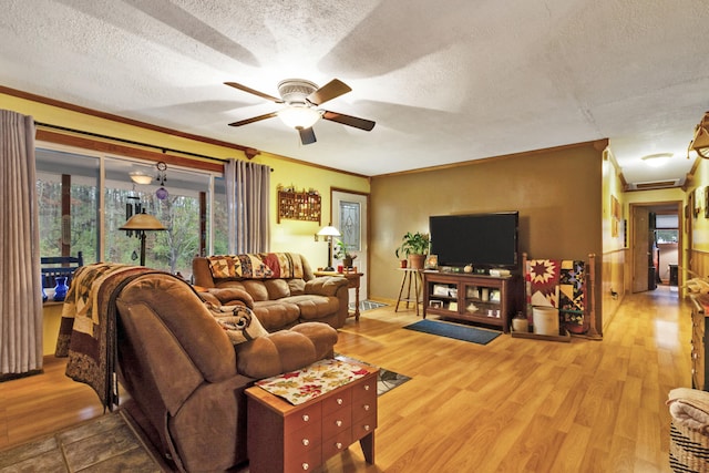 living room featuring a textured ceiling, light hardwood / wood-style floors, ceiling fan, and crown molding