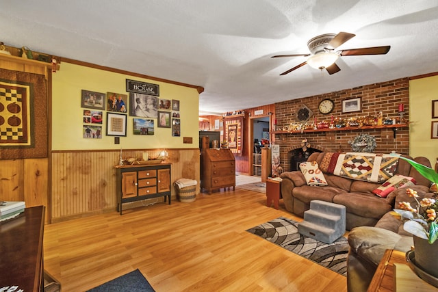 living room with a textured ceiling, light hardwood / wood-style floors, ceiling fan, and crown molding