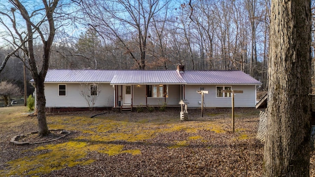 ranch-style house with covered porch, metal roof, and a chimney