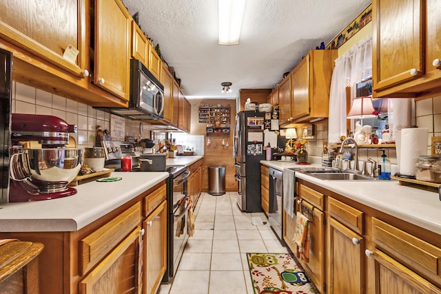 kitchen with sink, decorative backsplash, a textured ceiling, light tile patterned flooring, and stainless steel appliances