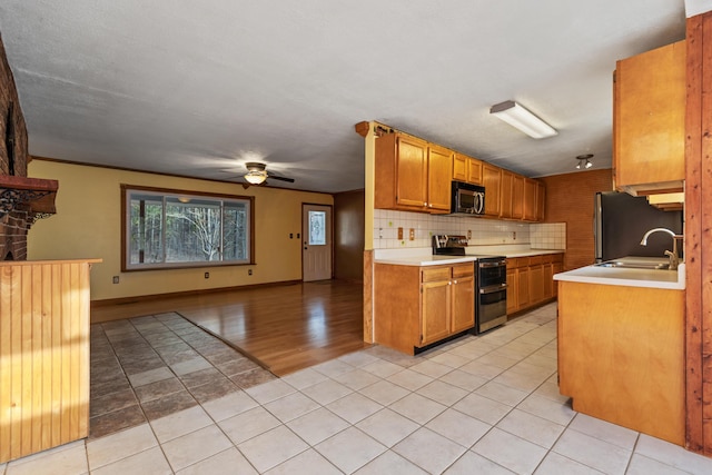 kitchen featuring stainless steel appliances, light countertops, brown cabinetry, open floor plan, and ceiling fan