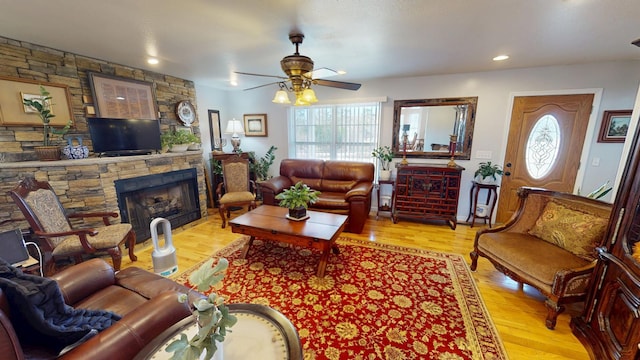 living room with light hardwood / wood-style flooring, a stone fireplace, and a wealth of natural light