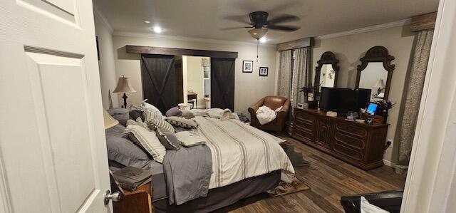 bedroom featuring ceiling fan, a barn door, crown molding, and dark wood-type flooring