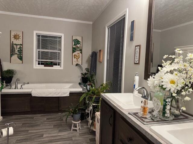 bathroom featuring vanity, a bathing tub, ornamental molding, a textured ceiling, and wood-type flooring