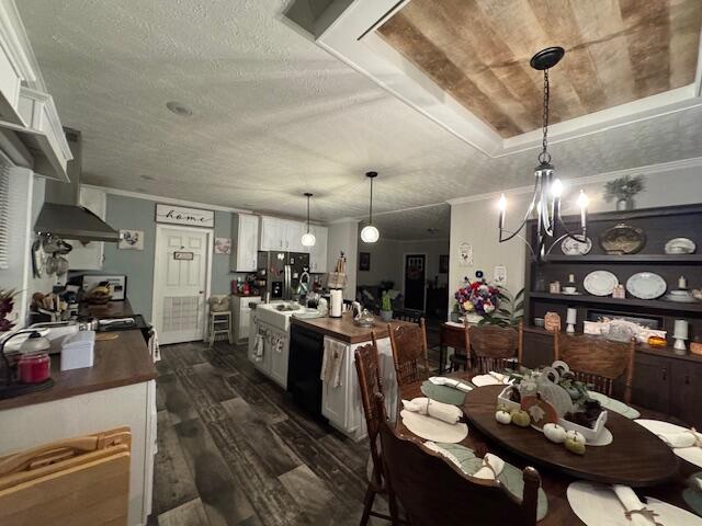 dining space featuring dark hardwood / wood-style flooring, a textured ceiling, a raised ceiling, sink, and a chandelier