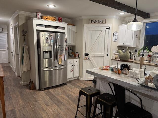 kitchen with stainless steel fridge, white cabinetry, pendant lighting, and beam ceiling