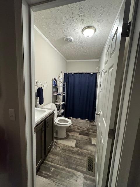 bathroom with vanity, crown molding, hardwood / wood-style flooring, toilet, and a textured ceiling