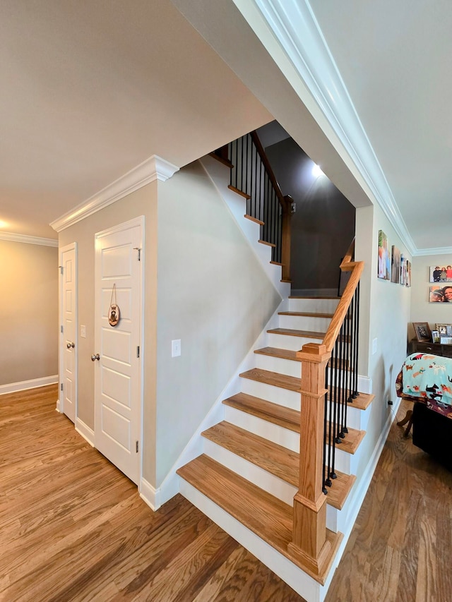 stairway featuring hardwood / wood-style floors and crown molding