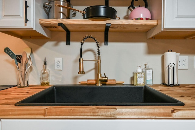 interior details featuring white cabinets, sink, and wooden counters