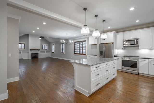 kitchen featuring hanging light fixtures, stainless steel appliances, a center island, a large fireplace, and white cabinets