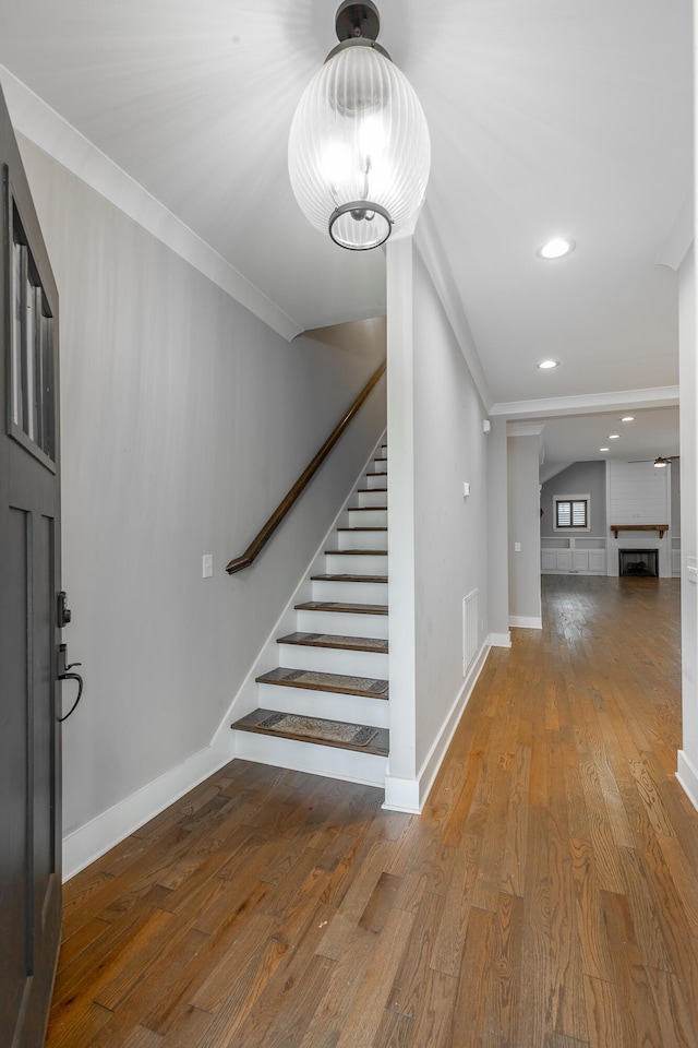 foyer featuring hardwood / wood-style flooring, a fireplace, and ornamental molding