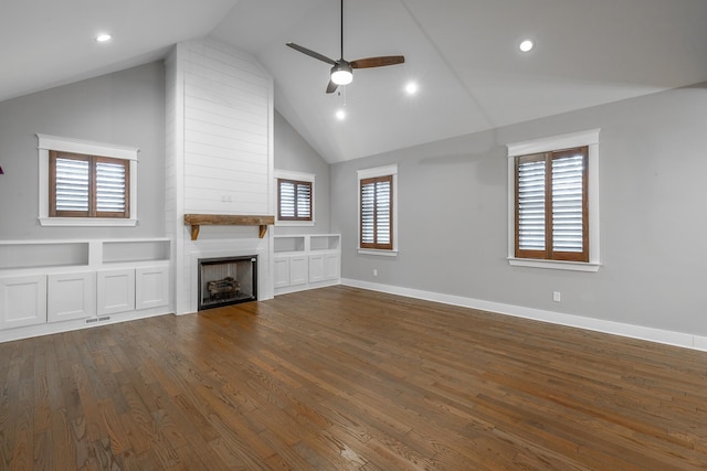 unfurnished living room with dark hardwood / wood-style flooring, ceiling fan, a large fireplace, and a healthy amount of sunlight