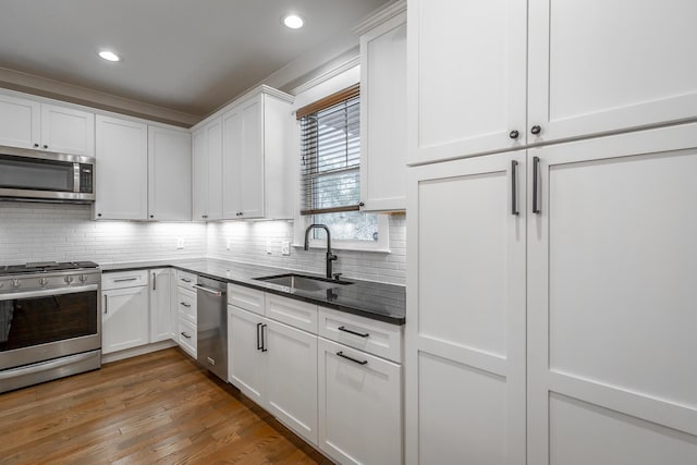 kitchen featuring sink, stainless steel appliances, tasteful backsplash, white cabinets, and dark hardwood / wood-style flooring