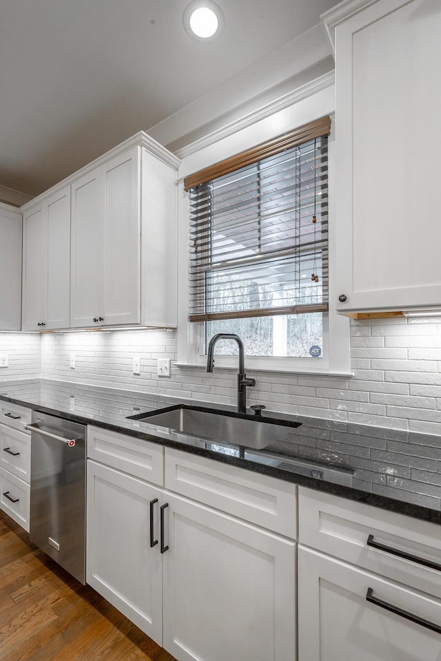 kitchen with tasteful backsplash, sink, dark stone countertops, white cabinets, and stainless steel dishwasher