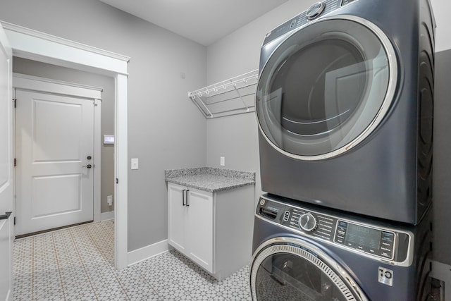 laundry room featuring cabinets and stacked washing maching and dryer