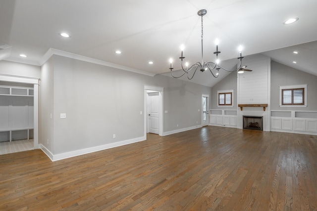 unfurnished living room with crown molding, vaulted ceiling, a large fireplace, dark hardwood / wood-style floors, and ceiling fan with notable chandelier