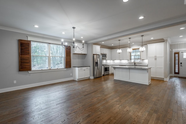 kitchen with stainless steel appliances, ornamental molding, white cabinets, a kitchen island, and decorative light fixtures