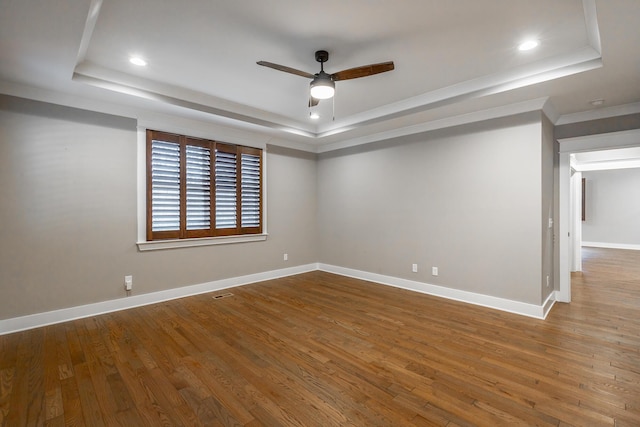 spare room with crown molding, ceiling fan, a raised ceiling, and hardwood / wood-style floors