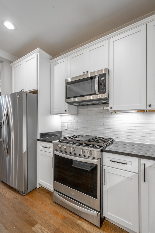 kitchen with tasteful backsplash, appliances with stainless steel finishes, and white cabinets