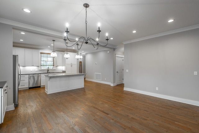 kitchen featuring stainless steel appliances, ornamental molding, white cabinets, a kitchen island, and decorative light fixtures