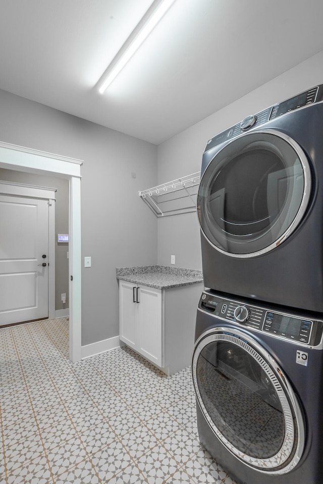 laundry room with stacked washer / drying machine and cabinets