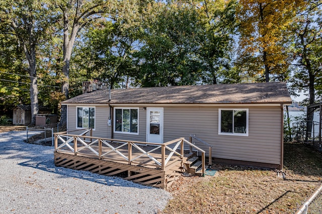 rear view of house with a wooden deck and a storage shed