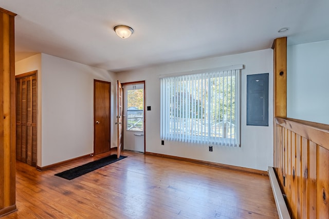 empty room with baseboard heating, electric panel, and light hardwood / wood-style floors