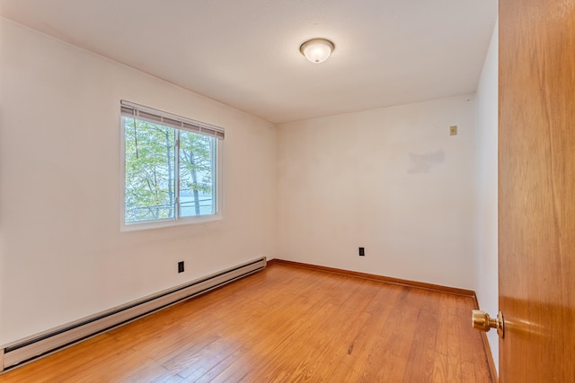 spare room featuring a baseboard radiator and light hardwood / wood-style floors