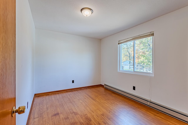 spare room with wood-type flooring, a textured ceiling, and a baseboard radiator