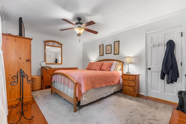 bedroom featuring ceiling fan, light wood-type flooring, and crown molding