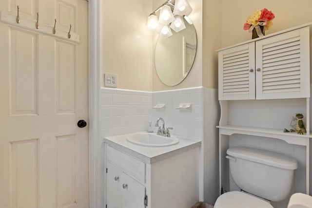 bathroom with vanity, toilet, and tile walls