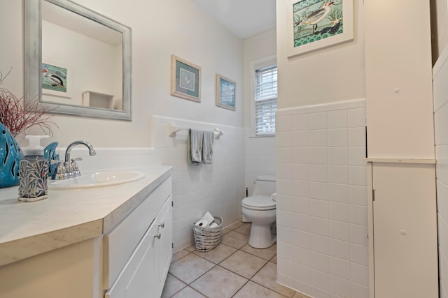 bathroom featuring toilet, vanity, tile patterned floors, and tile walls