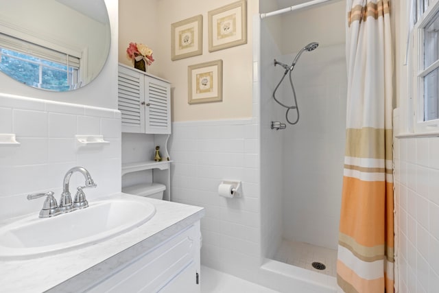 bathroom featuring vanity, curtained shower, and tile walls