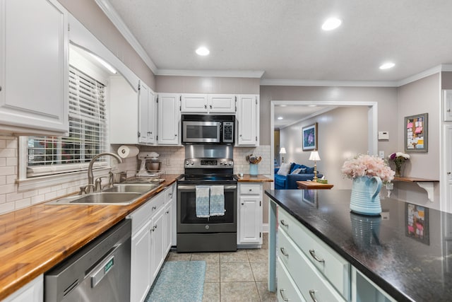 kitchen featuring white cabinetry, sink, appliances with stainless steel finishes, light tile patterned flooring, and ornamental molding