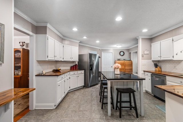 kitchen featuring white cabinets, a kitchen breakfast bar, ornamental molding, and appliances with stainless steel finishes