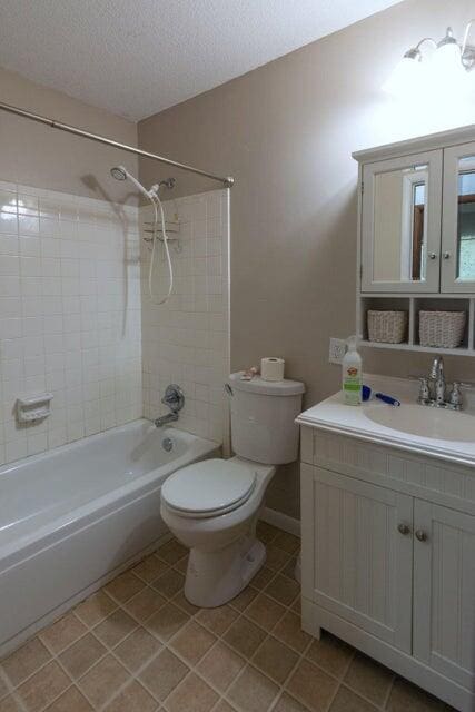 full bathroom with vanity, a textured ceiling, tile patterned flooring, toilet, and tiled shower / bath