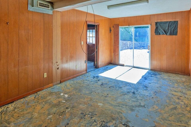 unfurnished room featuring wooden walls and carpet floors