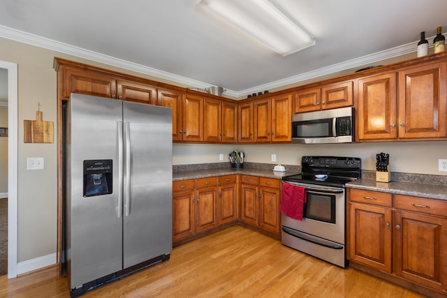 kitchen with brown cabinetry, stainless steel appliances, ornamental molding, dark countertops, and light wood-type flooring