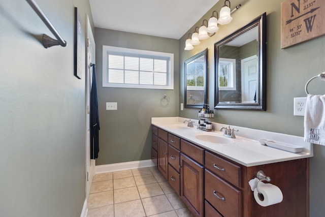 bathroom with double vanity, a sink, tile patterned floors, and baseboards